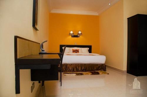 a bedroom with a bed and a desk next to a bed at EAGLES NEST INT. HOTEL in Tarkwa