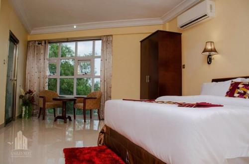 a bedroom with a bed and a table and a window at EAGLES NEST INT. HOTEL in Tarkwa