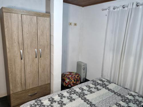 a bedroom with a bed and a wooden cabinet at Cantinho da Eli - Pousada com Piscina in Mairiporã