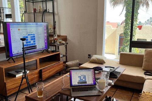 sala de estar con TV y mesa con ordenador portátil. en Casa amplia con vista de altura en Toluca