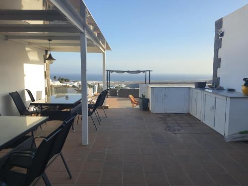 eine Terrasse mit Tischen und Stühlen und Meerblick in der Unterkunft Villa Feliza in Güime