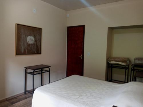 a bedroom with a white bed and two stools at Villa a arte de Minas in Tiradentes