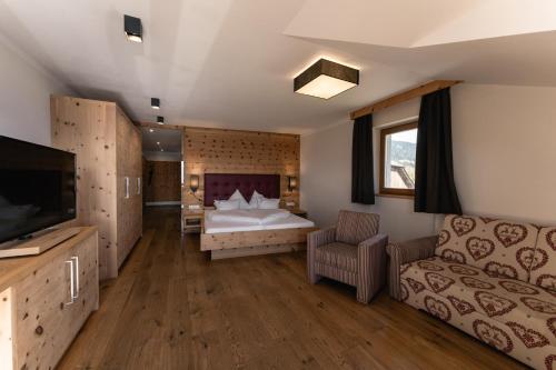 a bedroom with a bed and a couch at Panoramahotel Huberhof in Maranza