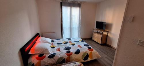 a small bedroom with a bed and a television at Grand studio confortable jusqu'à 4 personnes in Digne-les-Bains