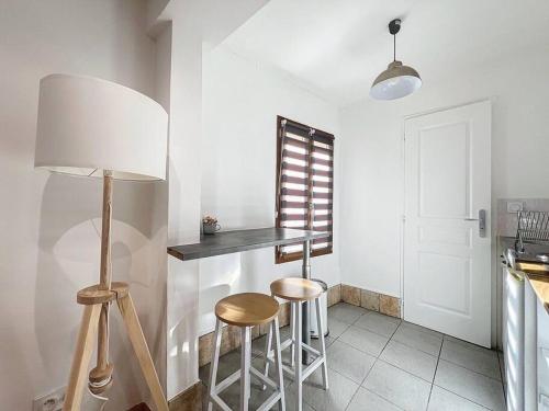 une cuisine avec deux tabourets, une table et une lampe dans l'établissement Appartement Isle-sur-la-Sorgue, à LʼIsle-sur-la-Sorgue