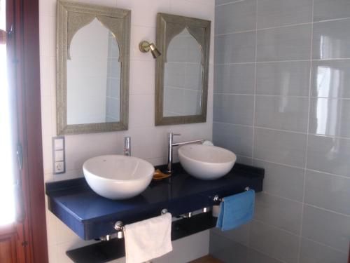 a bathroom with two sinks and two mirrors at Cerro del Pozo in Las Hoyas del Barranco