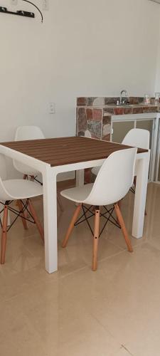 una mesa de madera con 2 sillas blancas alrededor en Casa Blanca, 
