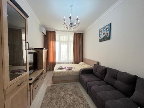 ein Wohnzimmer mit einem Sofa und einem Bett in der Unterkunft Однокомнатные бизнес апартаменты в ЖК Заман in Atyrau