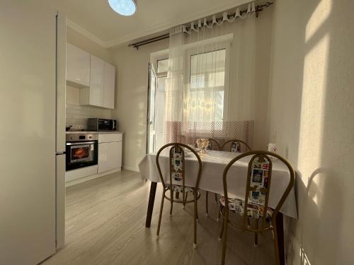 eine Küche mit einem weißen Tisch und 2 Stühlen in der Unterkunft Однокомнатные бизнес апартаменты в ЖК Заман in Atyrau