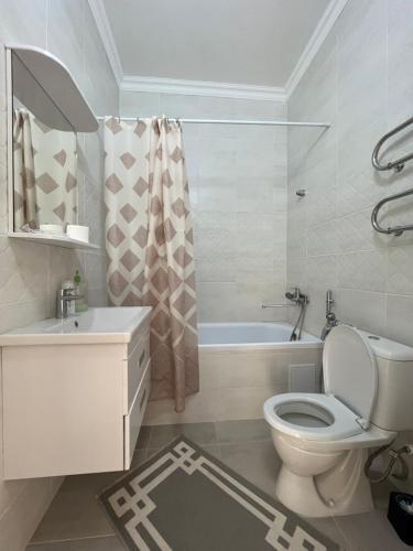 ein weißes Bad mit einem WC und einer Badewanne in der Unterkunft Однокомнатные бизнес апартаменты в ЖК Заман in Atyrau