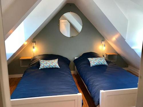 2 bedden in een zolderkamer met een spiegel bij Maison grande terrasse magnifique vue sur l'Aber Wrac'h in Landéda