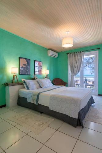 a bedroom with a large bed with green walls at Pousada dos Gravatás in Búzios