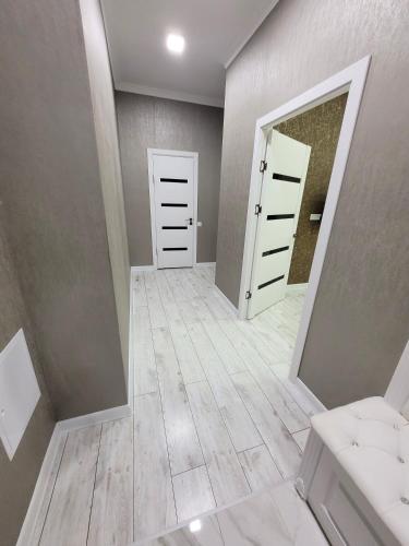 - un couloir avec deux portes blanches et un miroir dans l'établissement Однокомнатные бизнес апартаменты в ЖК Заман, à Atyraū
