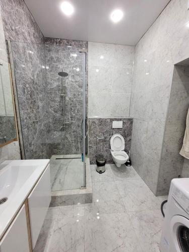 y baño con ducha, aseo y lavamanos. en Однокомнатные бизнес апартаменты в ЖК Заман, en Atyraū