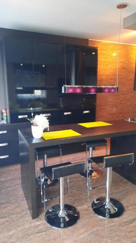 a kitchen with a black island with bar stools at Modern Art Apartment im Zentrum Weiden in Weiden