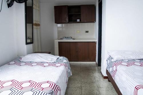2 camas en una habitación pequeña con cocina en hospedaje oasis central en Palmira