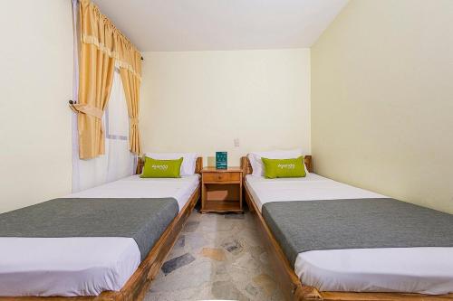 um quarto com duas camas e uma mesa com uma janela em Hotel El Bosque em Armênia