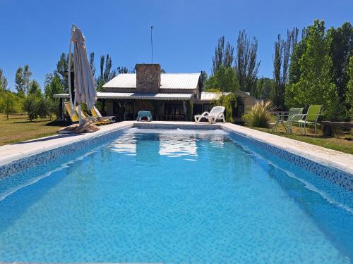 una gran piscina con 2 sillas y una casa en El Madejo - del Valle de Uco en Tunuyán
