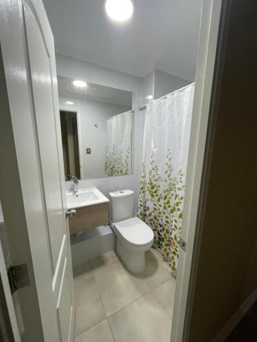 a white bathroom with a toilet and a sink at Departamento La Serena por Días in La Serena