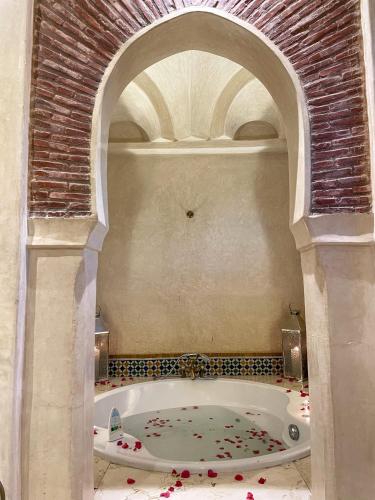 a bathroom with a tub with red flowers in it at Villa Taj Sofia & Spa in Marrakech