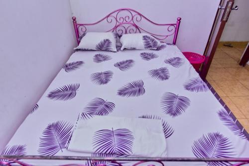 a bed with a white bedspread with leaves on it at NoorVilla in Arusha