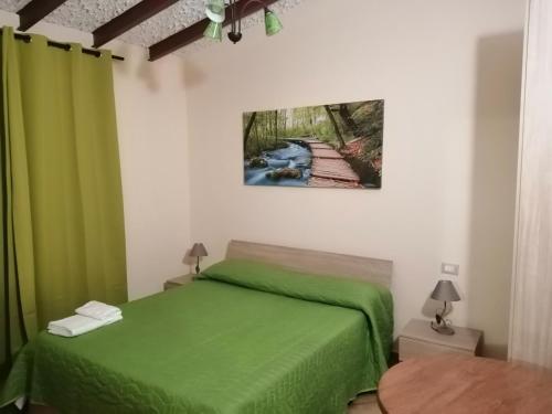 una camera con un letto verde e un dipinto sul muro di Baglio delle Rondini - Piano Terra a Bagheria