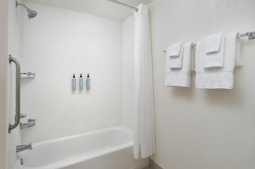 La salle de bains est pourvue d'une baignoire et de serviettes blanches. dans l'établissement Courtyard Baton Rouge Siegen Lane, à Bâton-Rouge