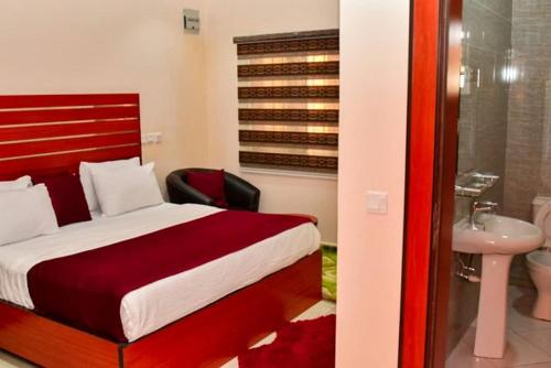 a bedroom with a bed and a bathroom with a sink at Alim Royal Hotel and Suites in Abuja