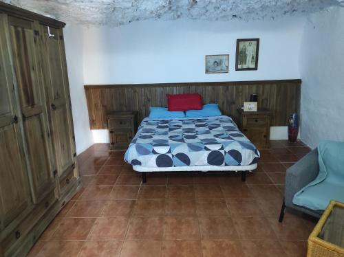 a bedroom with a bed and a chair at Casa Cueva Manuel y María in El Juncal