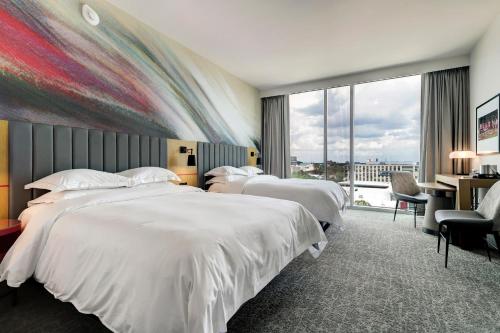 um quarto de hotel com três camas e uma grande janela em Hilton University of Houston em Houston