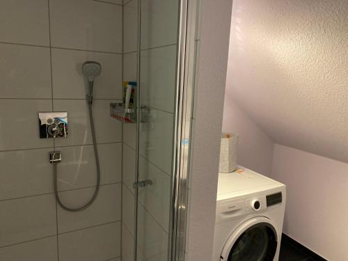 een badkamer met een douche en een wasmachine bij Zimmer am Bachlauf in Gelsenkirchen