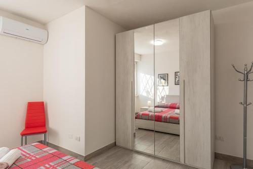 a bedroom with a mirrored closet with a red chair at White Angel in Castelnuovo del Garda