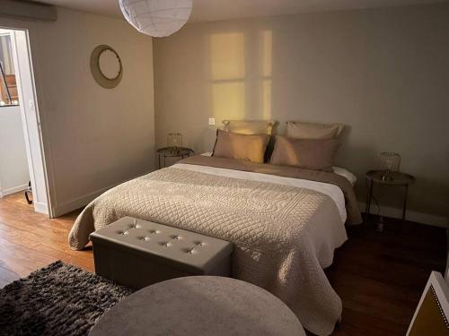 a bedroom with a large bed with a ottoman at La Har'Elle in Château-Gontier