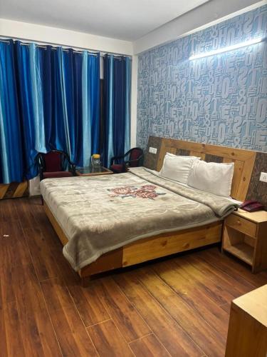 Asha Residency Shimla - Airport Road في شيملا: غرفة نوم بسرير كبير مع ستائر زرقاء