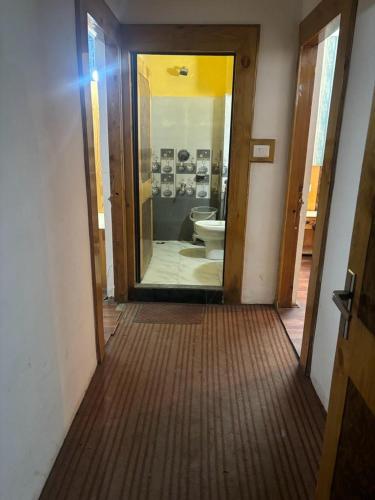 a hallway of a bathroom with a toilet and a doorway at Asha Residency Shimla - Airport Road in Shimla