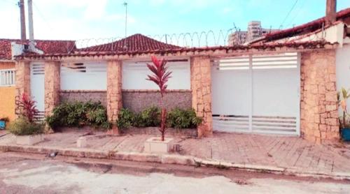 une maison en briques avec deux portes de garage et un palmier dans l'établissement Recanto Caiçara, à Solemar