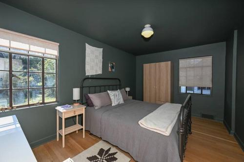 ein Schlafzimmer mit einem Bett, einem Tisch und zwei Fenstern in der Unterkunft SuperHost PLUS ~ Designer Inspired Boynton Bungalow in Cleveland Heights