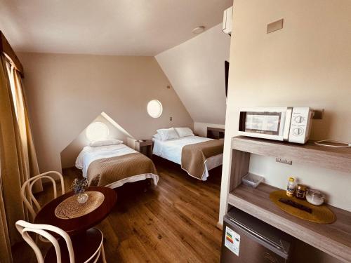 Habitación pequeña con 2 camas y mesa en Hotel Casona Los Colonos en Valdivia