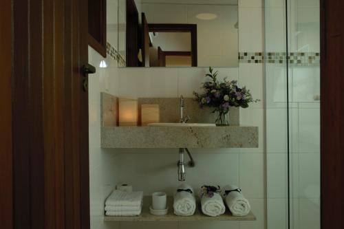 a bathroom with a sink and a mirror and towels at Vila dos Caetés - Suíte 02 - Barra do Sahy in Barra do Sahy