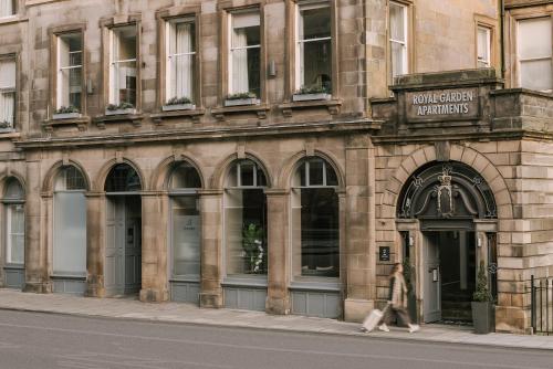 a woman walking down a street in front of a building at Sonder Royal Garden in Edinburgh