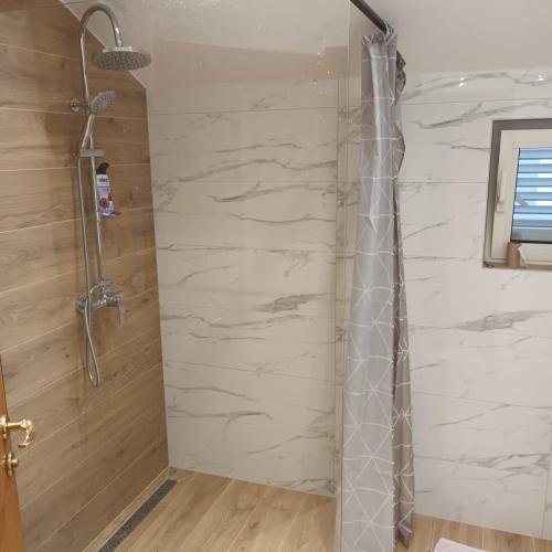 a shower in a bathroom with a stone wall at Apartments "Jope i Toni" in Biograd na Moru