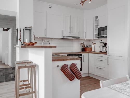 a white kitchen with white cabinets and a wooden stool at Åre Valley Lodges - Ytterstmyrvägen 19D in Åre