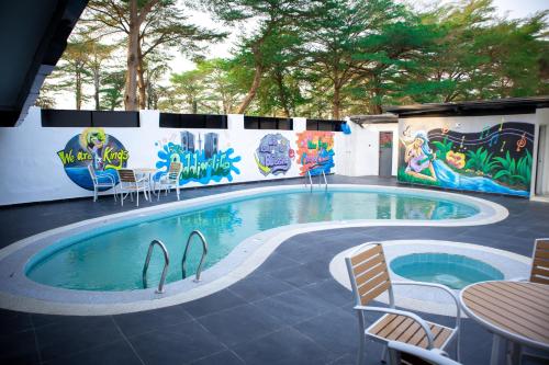 a swimming pool with chairs and a table and a mural at Portland Suites in Abuja