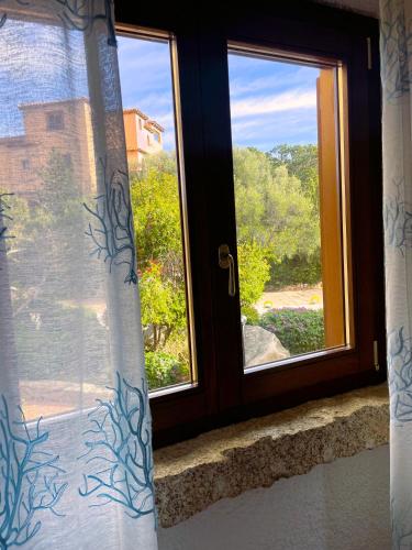 a window with a view of a yard at Porto Rotondo centro - splendido appartamento con terrazza in Porto Rotondo