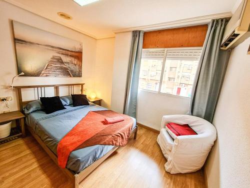 a bedroom with a bed and a chair and a window at Apartamento Olímpico en Murcia in Murcia