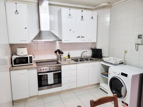 a kitchen with white cabinets and a sink and a dishwasher at Apartamento Olímpico en Murcia in Murcia