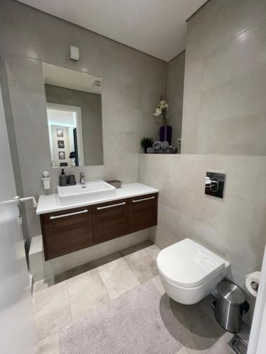 uma casa de banho com um WC, um lavatório e um espelho. em Luxury Appartment Belgrade Waterfront em Belgrado