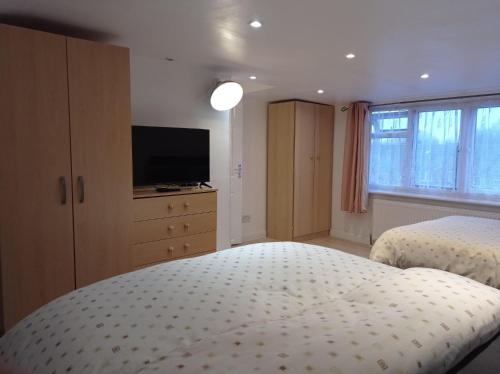a bedroom with two beds and a flat screen tv at Shepherds Spacious House 4-Beds in Romford