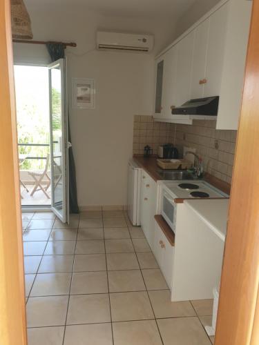 a kitchen with white cabinets and a tile floor at Maresia Apts & Studios in Arillas