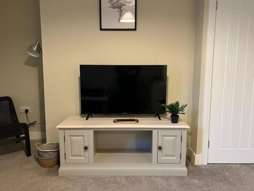 a tv sitting on top of a white entertainment center at Well Equipped Apartment In Stoke on Trent in Stoke on Trent